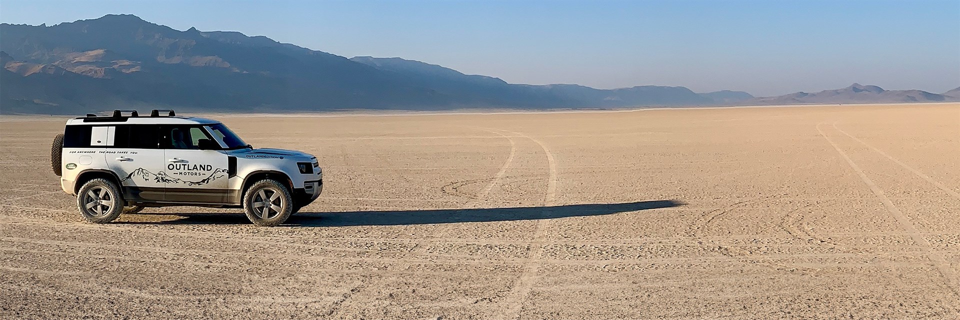 outland motors SUV in dessert with mountain view