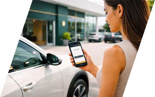 Customer viewing an instant car trade-in valuation on a smartphone beside their vehicle at a modern dealership