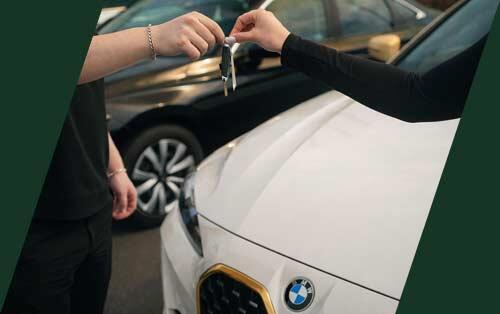 Customer receiving car keys at Warrington Auto Sales dealership in Warrington PA in front of BMW vehicle